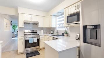 A modern kitchen with stainless steel appliances, white cabinetry, and a large island.