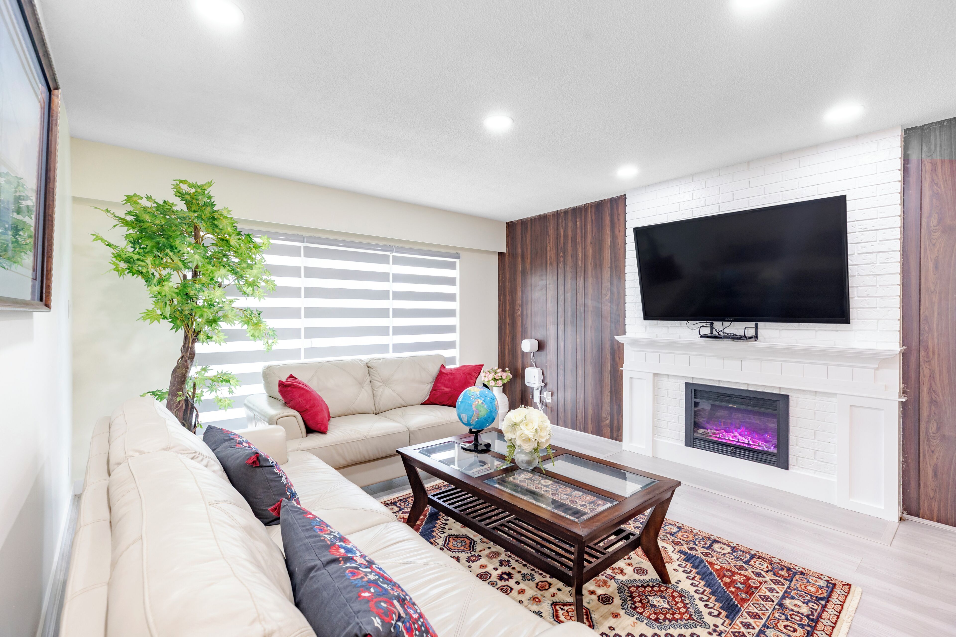 A living room with a sofa, a coffee table, a fireplace, and a television.