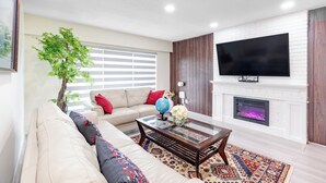A living room with a sofa, a coffee table, a fireplace, and a television. - Vancouver Verdant Villa (Vancouver)
