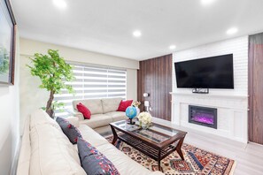 A living room with a sofa, a coffee table, a fireplace, and a television. - Vancouver Verdant Villa (Vancouver)