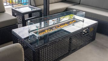 A glass-top coffee table with a decorative item inside, placed on a wicker sofa.