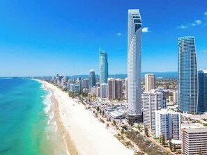 A coastal cityscape with high-rise buildings, a beach, and clear skies. - [SEA BREEZE] North East Ocean View Studio @ Mantra Legends (Surfers Paradise)