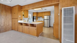 Una cocina con gabinetes de madera, un refrigerador de acero inoxidable y un microondas integrado.