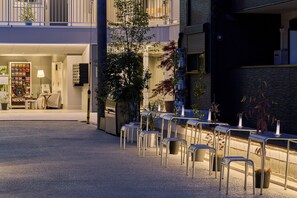 A courtyard with outdoor seating, a Nescafe machine, and a building entrance.
