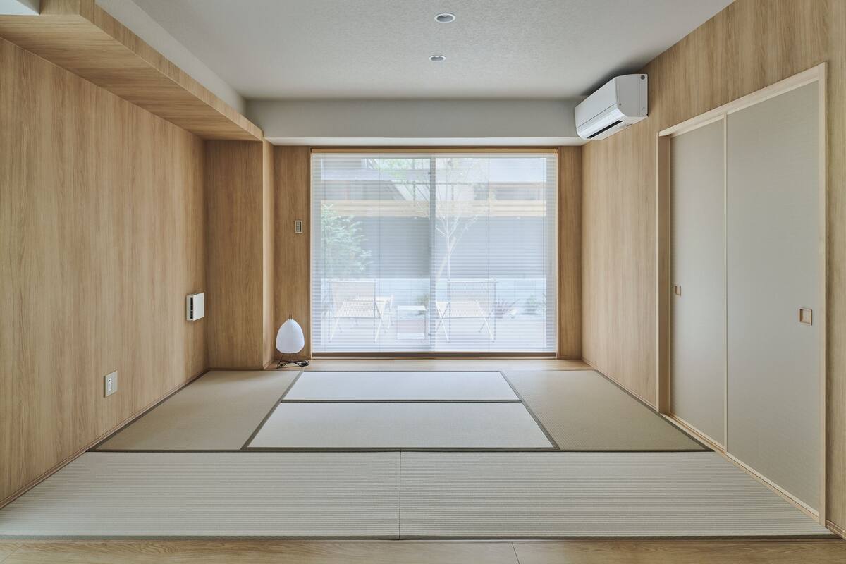 A room with tatami flooring, a sliding door, and a ceiling-mounted air conditioner.