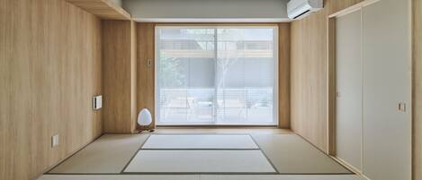 Una habitación con suelo de tatami, puertas correderas y aire acondicionado instalado en el techo.