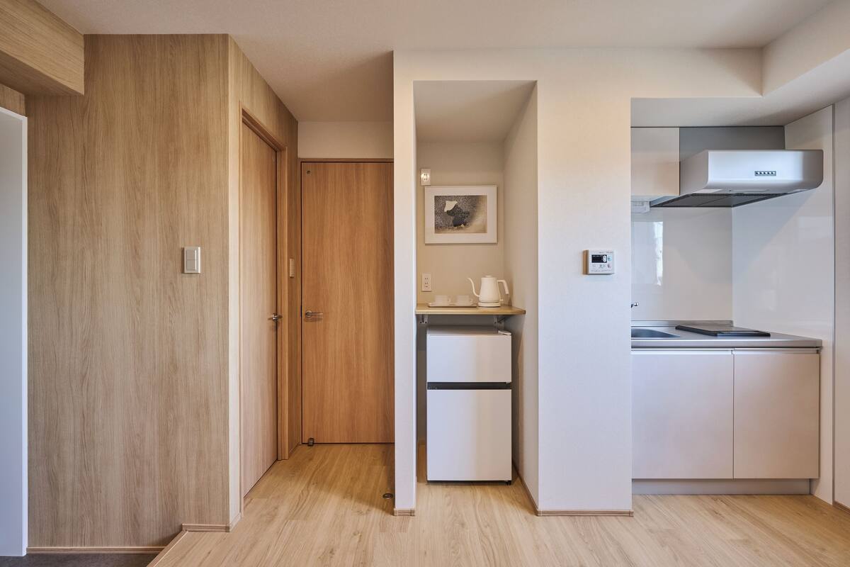 A compact kitchen with a built-in oven, a microwave, and a stainless steel range hood.