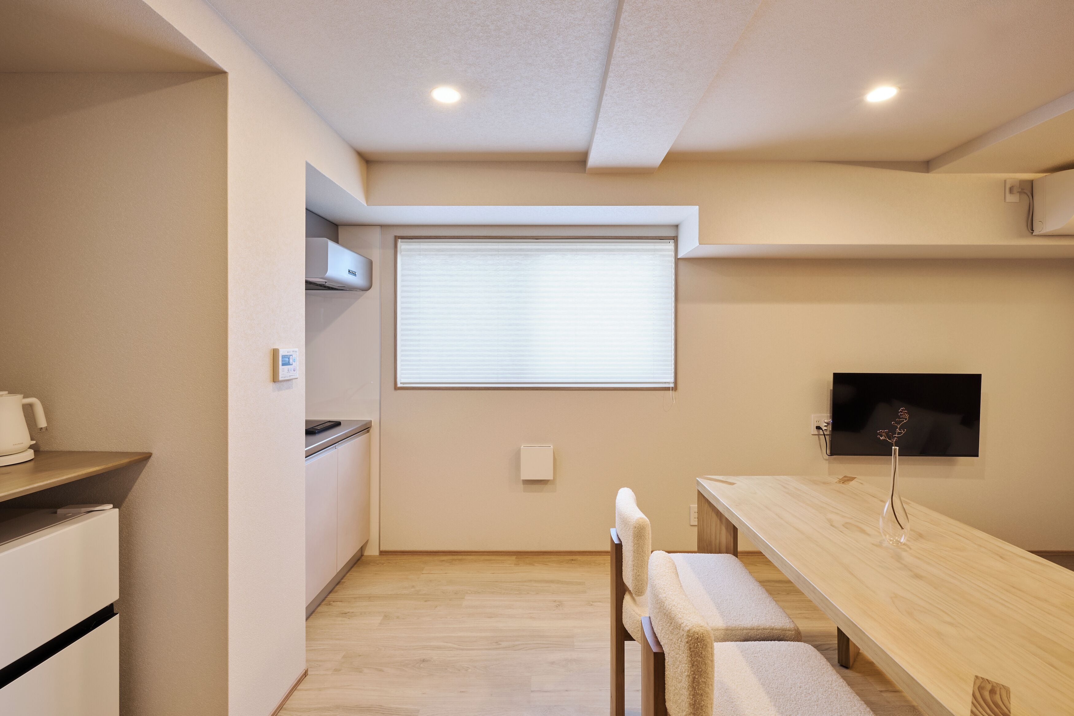 Een moderne keuken met een ingebouwde oven, een eettafel met stoelen en een aan de muur bevestigde televisie.