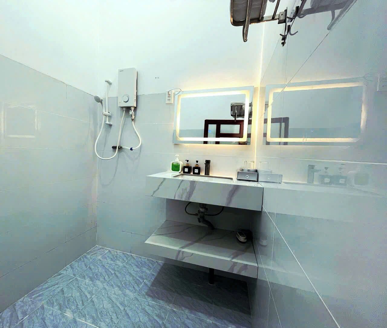 Een moderne badkamer met een douche, een wastafel met spiegel, en een plank met toiletartikelen.