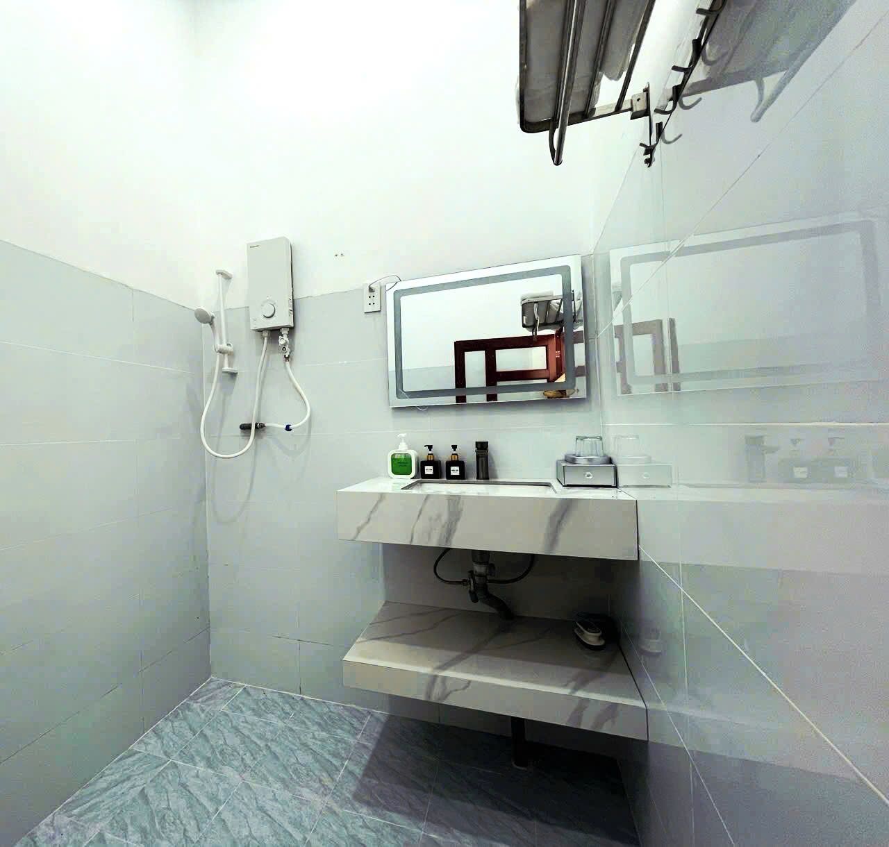 Een badkamer met een douche, een wastafel met toiletartikelen en een spiegel.