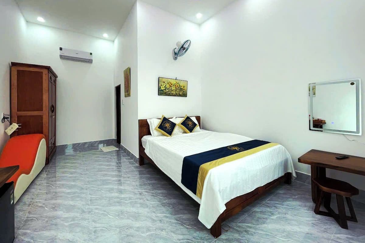 Habitación de hotel con cama, mesita de noche, silla, escritorio y espejo.