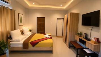 A hotel room with a bed, a TV, a desk, and a door.
