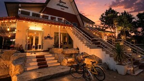 A building with a staircase leading to a covered entrance, a bicycle parked outside, and large rocks at the base of the stairs.