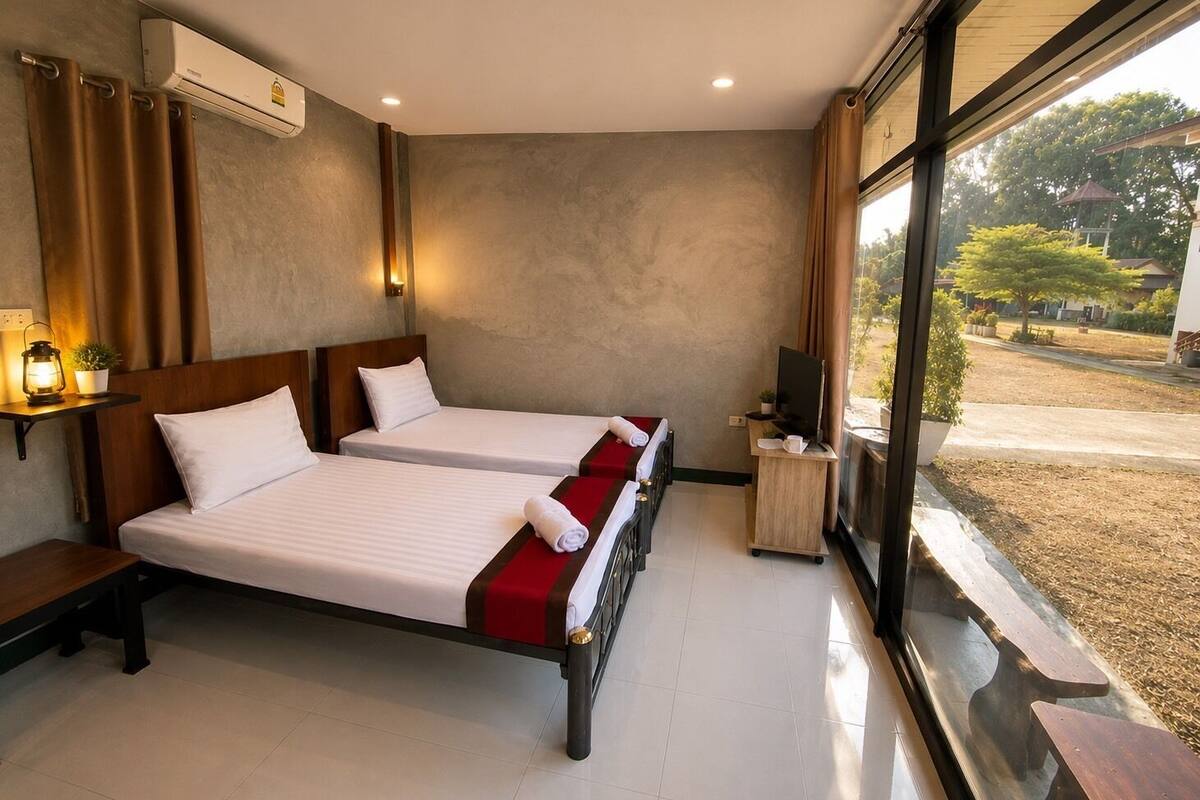 Habitación de hotel con dos camas, televisor, una mesita y ventana con vista al exterior.