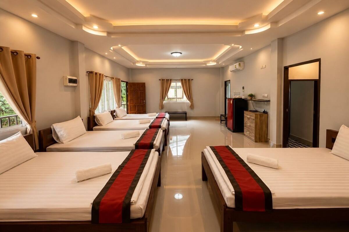 Habitación de hotel con cuatro camas, un televisor, un armario y una puerta que da a un balcón.