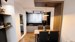Una cucina moderna con zona pranzo, soffitto in legno e lampada a sospensione.