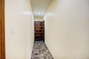 A narrow hallway with a tiled floor leading to a wooden door.