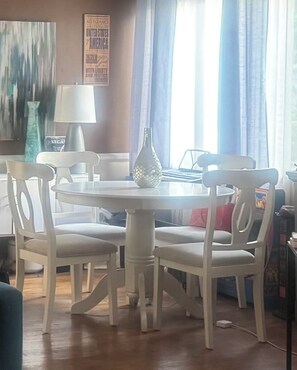 Ein Essbereich mit einem runden Tisch, vier Stühlen, einer Vase und einer Lampe.