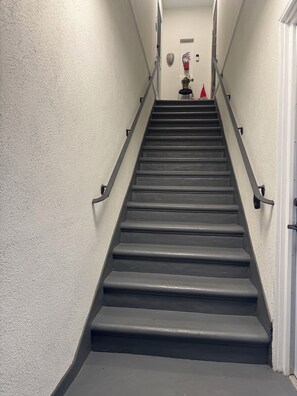 Eine Treppe mit Geländern, einem Feuerlöscher und einem kleinen dekorativen Gegenstand an der Wand.