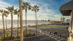A street view with palm trees, a pedestrian crossing, and a view of the ocean. - Unwind In Premium Beach-front Resort with Panoramic Ocean Views. 1Bd w/ Balcony (Carlsbad)