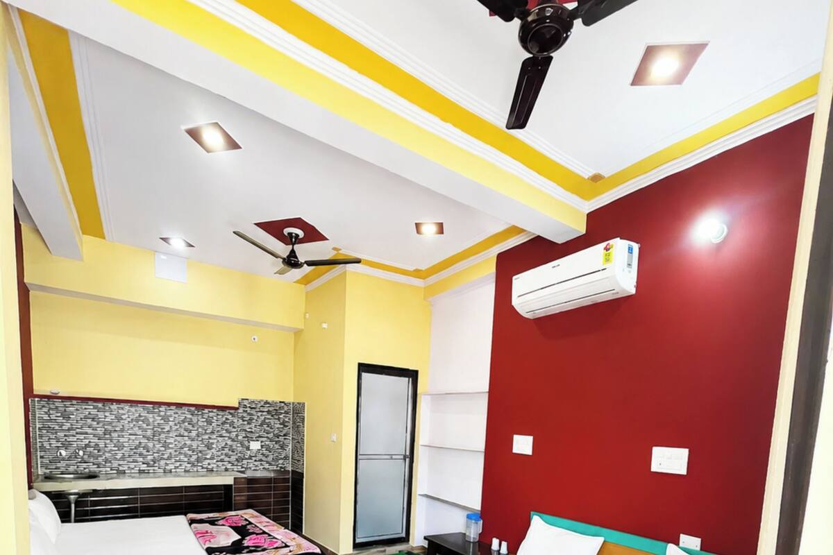 A bedroom with a bed, a desk, a chair, a ceiling fan, and an air conditioning unit.