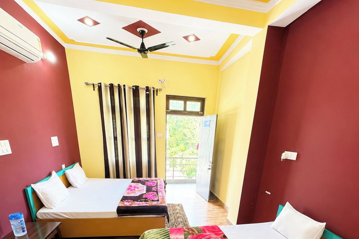 A hotel room with two beds, a desk, and a window with curtains.