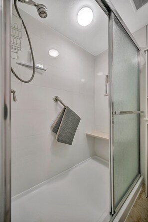 A modern bathroom with a glass shower enclosure, a handheld showerhead, and a towel rack. - Bermuda Bay Beachside Condo (St. Petersburg)