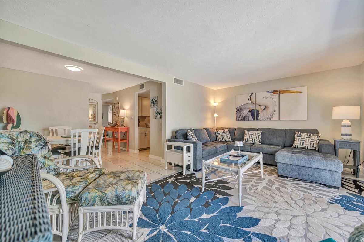 A living room with a sofa, armchair, coffee table, and a patterned rug.