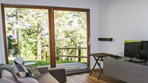 Ein modernes Wohnzimmer mit einer Couch, einem Fernseher auf einem Schrank und einer Schiebetür zu einem Außenbereich.