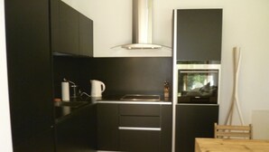Eine kleine Küche mit dunklen Schränken, einem Holztisch und einem Fenster.