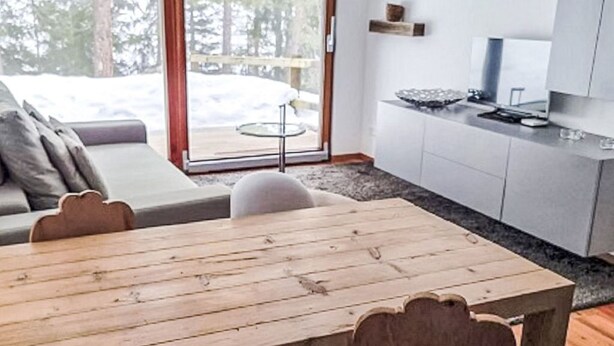 Ein modernes Interieur mit einem Holzes Esstisch, einer Couch und einer Küchenzeile.