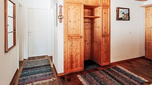 Un pasillo con armarios de madera, una puerta, un reloj de pared y un cuadro enmarcado.