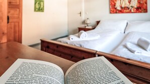 Una habitación de hotel con una cama, una mesita de noche y un libro abierto.