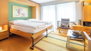 Quarto de hotel com cama, cadeira, escrivaninha e estante.