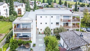 Un edificio residenziale moderno a più piani con balconi, un patio coperto e un giardino curato.