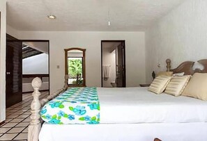 Ein Schlafzimmer mit Bett, Spiegel und einer Tür zu einem anderen Raum.