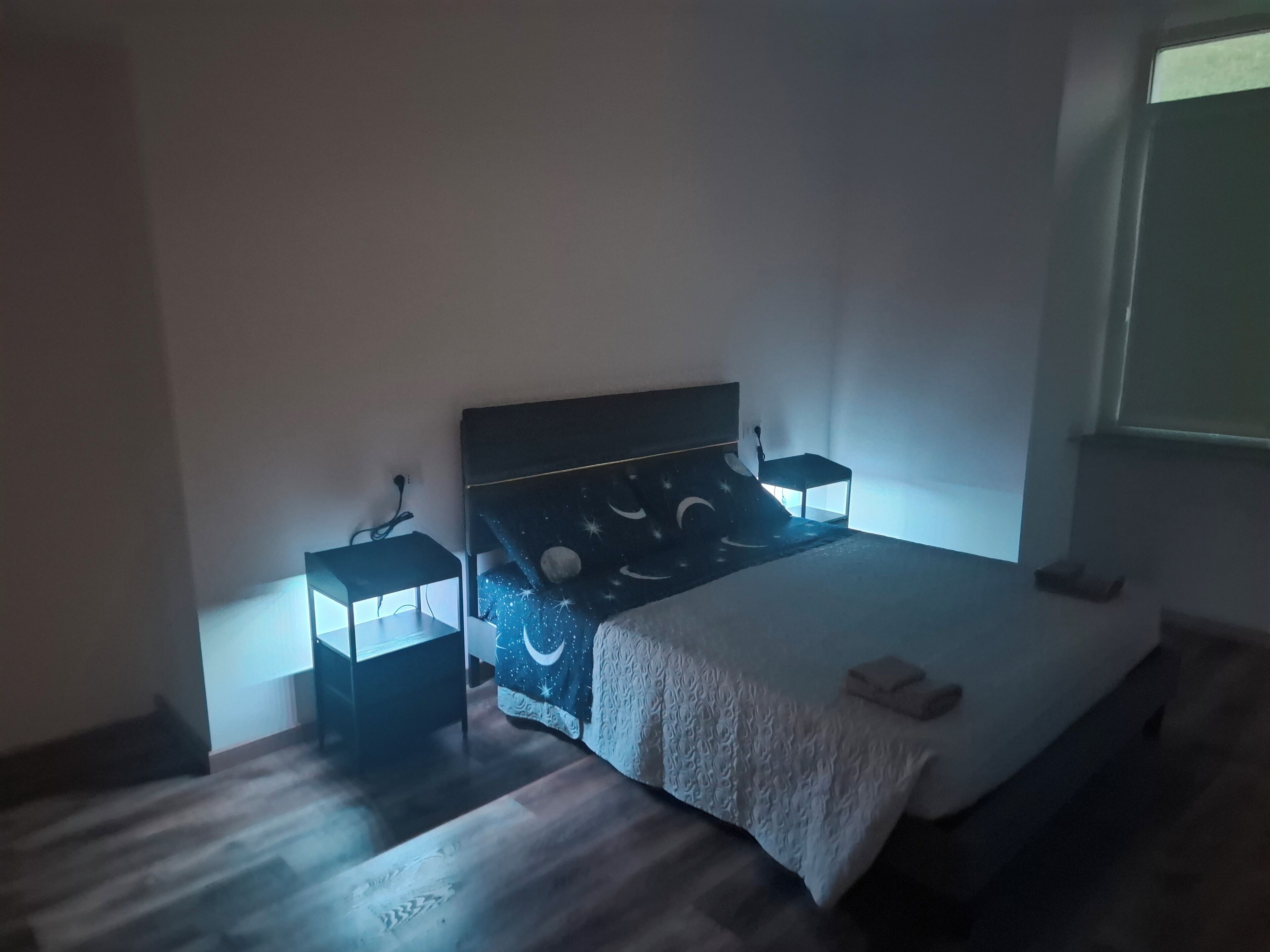 Ein Schlafzimmer mit einem Bett, Nachttischen, einem Fenster und Holzboden.