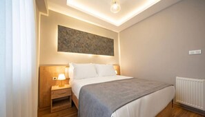 Ein Schlafzimmer mit Bett, Nachttisch, Lampe und Heizkörper.