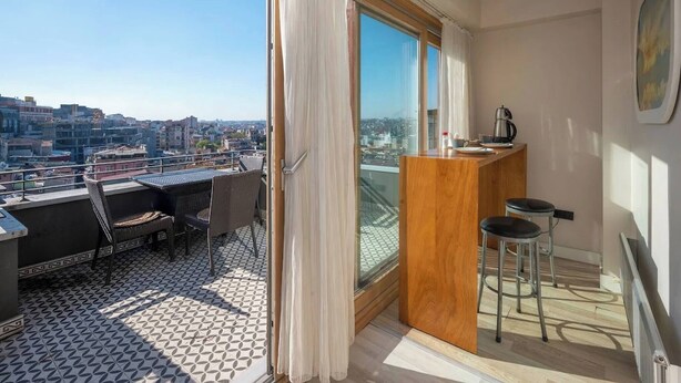 A balcony with a view of a cityscape, a wooden counter with a kettle, and a dining area with chairs. - Taksim Square-1BR Rooftop Suite 07 (Beyoğlu)