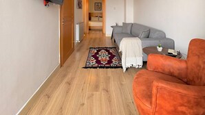 A hallway leading to a living area with a sofa, a television mounted on the wall, and a patterned rug. - Taksim Square-1BR Rooftop Suite 07 (Beyoğlu)