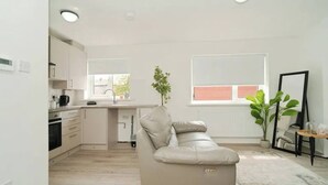 Une cuisine moderne avec des meubles blancs, un canapé beige et une plante en pot.