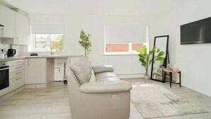 Une cuisine moderne avec des meubles blancs, un canapé beige et une grande fenêtre.