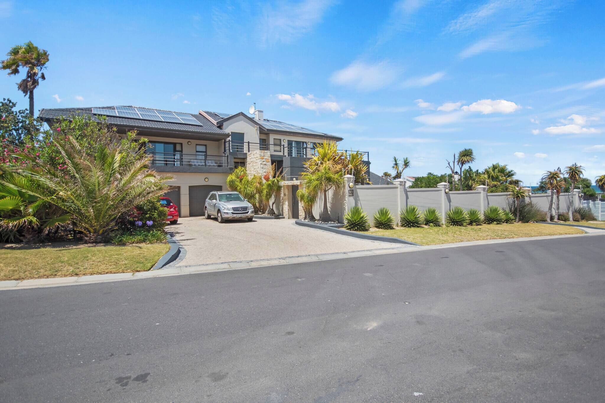 A modern two-story house with solar panels, a driveway, and a well-maintained lawn.