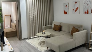 En moderne stue med en hjørnesofa, et rundt sofabord og en hængende pendel.