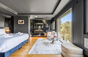A modern bedroom with a large bed, a seating area with a coffee table, and a view of the outdoors. - Magnificent 7 bedroom villa 10 minutes walk from Martinez (Cannes)