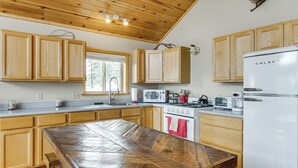 Eine Küche mit Holzschränken, einem weißen Kühlschrank, einem Herd und einer Mikrowelle.