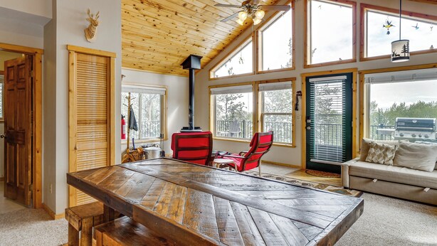 Ein Holztisch mit Bänken, ein roter Stuhl, eine Couch und ein Kamin.