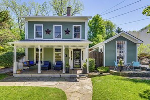 A two-story house with a porch, a small attached garage, and a stone pathway leading to the entrance. - Main St Retreat! 1895 Farmhouse in Port Jefferson (Port Jefferson)