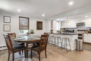 A modern kitchen with white cabinets, a central island, and bar stools. - Main St Retreat! 1895 Farmhouse in Port Jefferson (Port Jefferson)