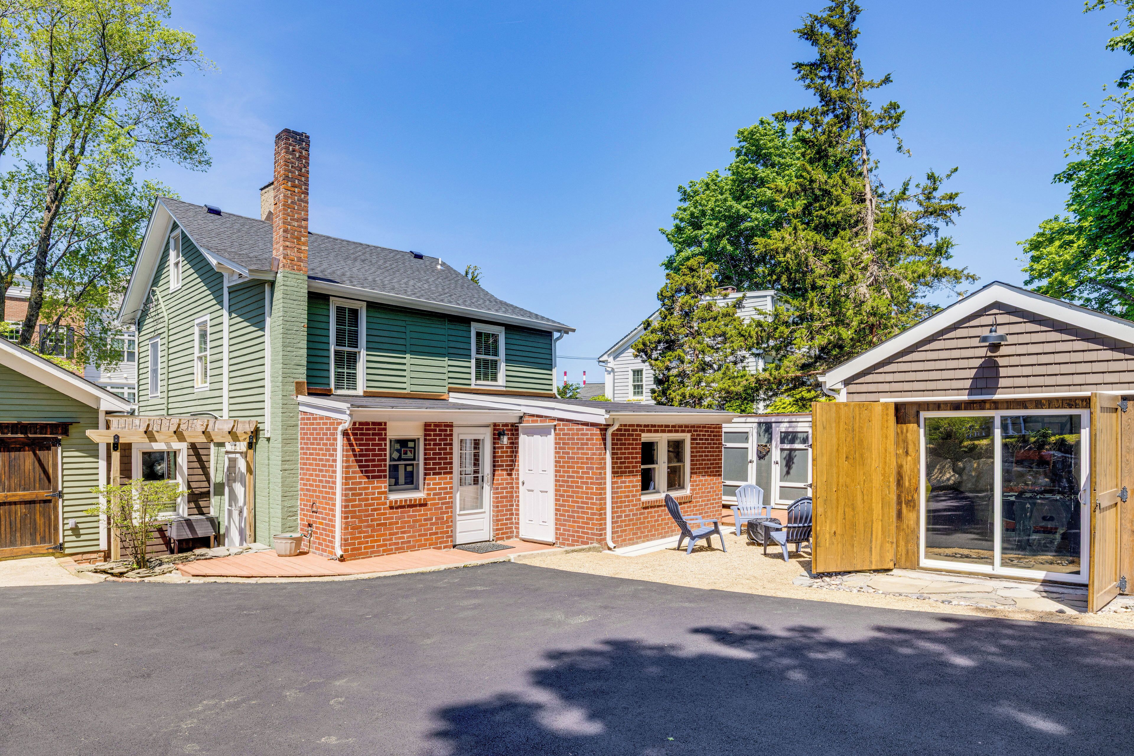 Une maison à deux étages avec une façade verte, une partie en briques et un garage en bois.